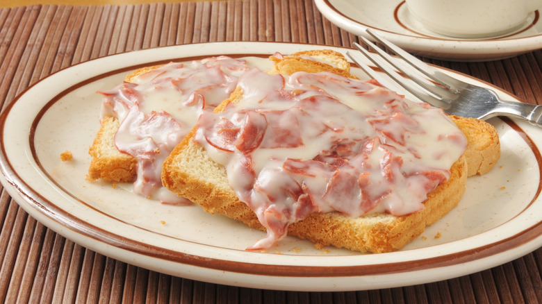 Chipped beef gravy on toast on a diner-style plate with a fork