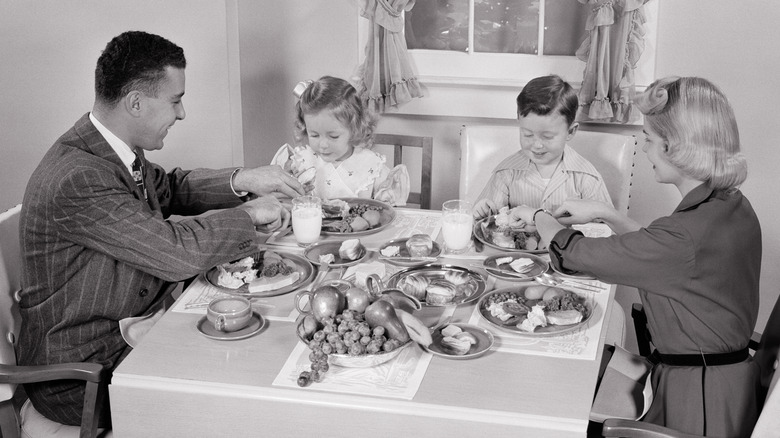 1950s family of four eating dinner at dining room table