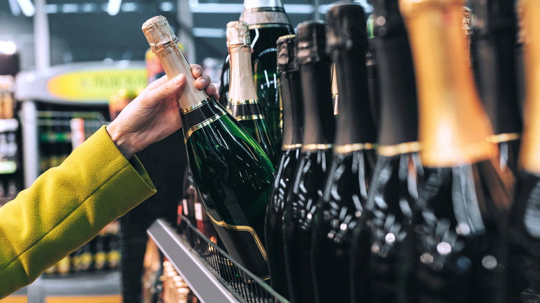 Hand taking a bottle of Champagne off the shelf in the store