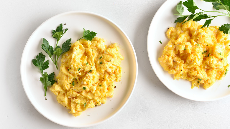 two plates of scrambled eggs with herbs