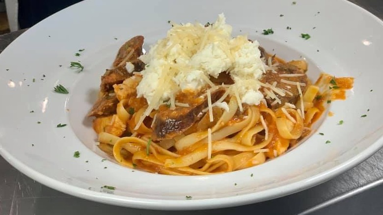 Plate of fettuccine in red sauce topped with ricotta and parmesan cheese