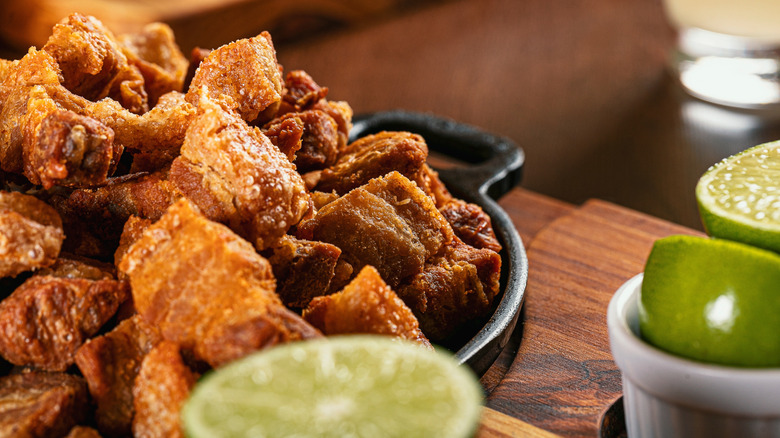 Close-up of pork cracklings in skillet with limes