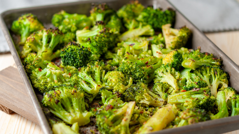 Smashed roasted broccoli on sheet tray with spices on top.
