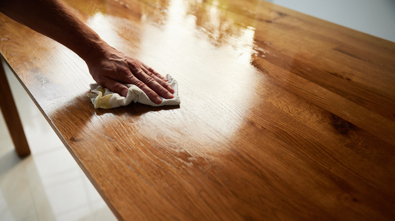 hand with rag oiling kitchen table