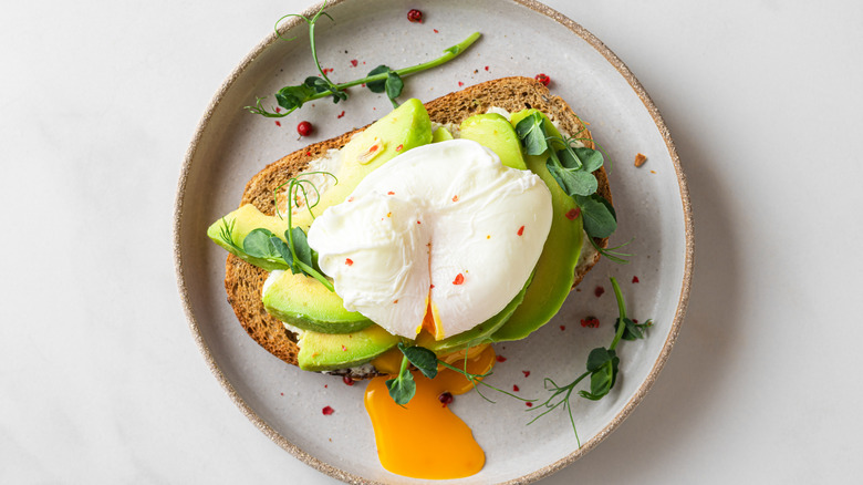 a plate of poached eggs on avocado toast