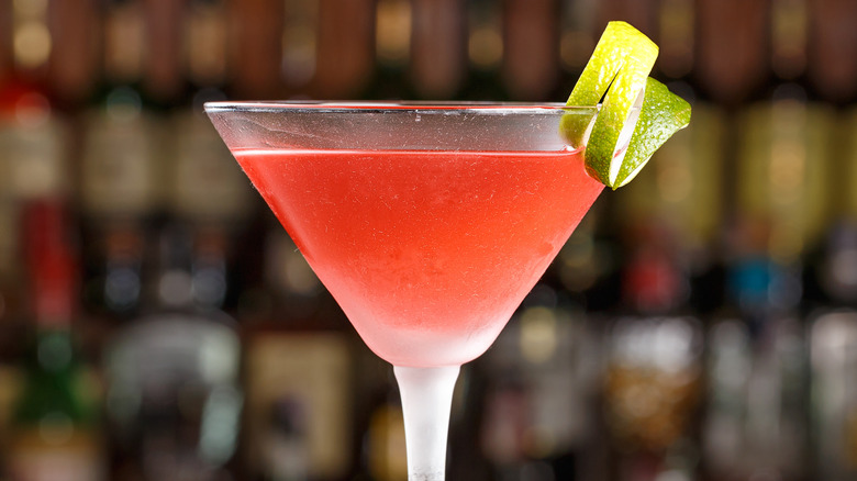 Cosmopolitan cocktail with a lime twist sitting on a bar