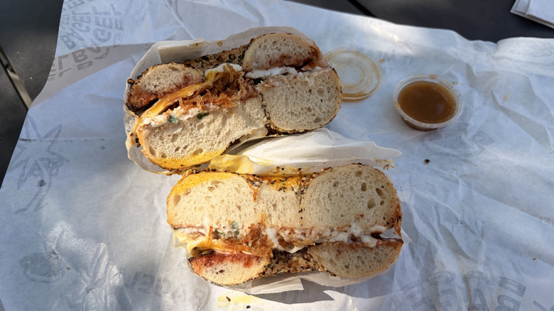 King Guava sandwich from El Bagel cut in half with side of Zab's hot sauce