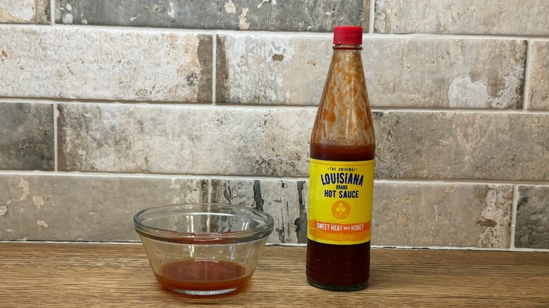 a bottle of Louisiana brand hot sauce next to a small bowl