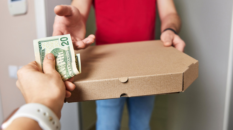 A person exchanges money for a pizza box