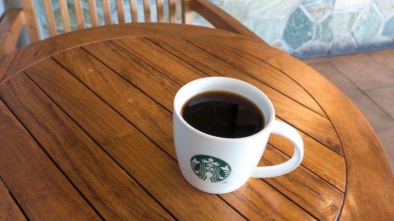 Starbucks mug with black coffee on wooden table