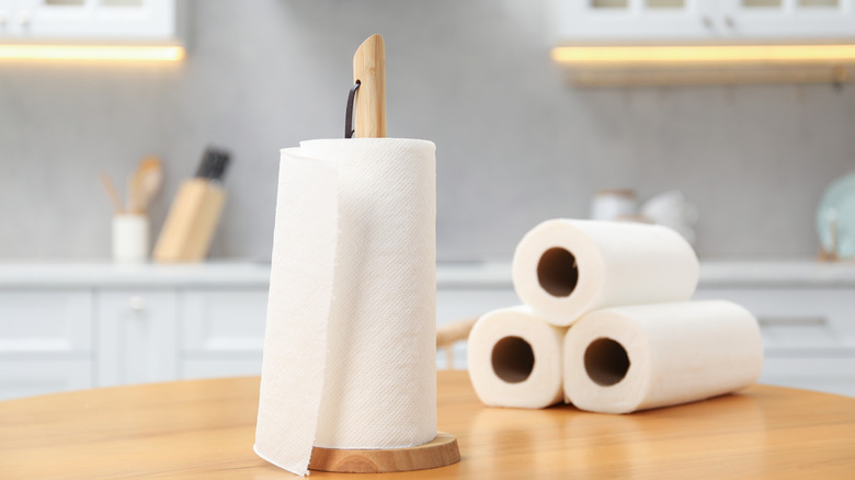 Roll of paper towels on holder with more rolls on kitchen counter