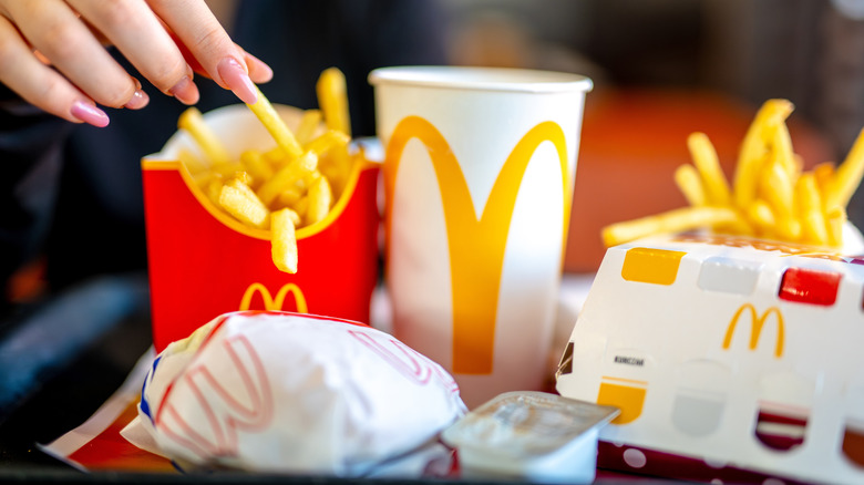 Hand grabbing McDonald's fries alongside burgers and drinks