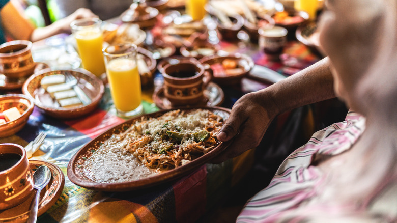 Waiter serving Mexican dish to brunch table filled with coffee cups and juice glasses