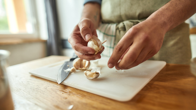 closeup of man peeling garlic in kitchen