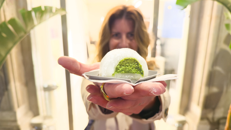 Woman holding out green tea mochi ice cream
