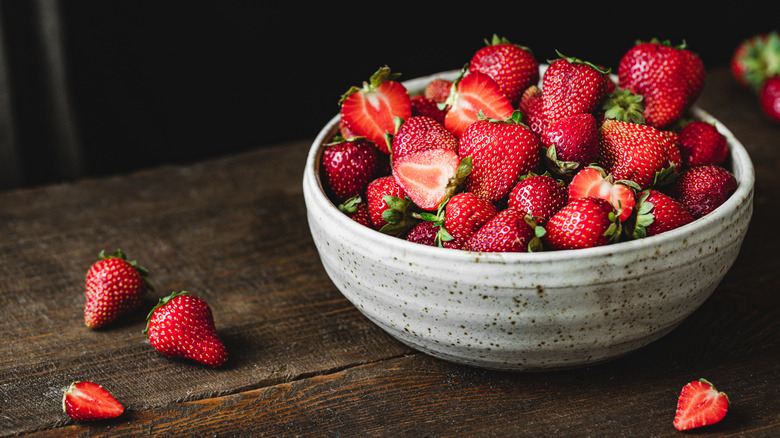 a bowl of fresh strawberries on a wooden table
