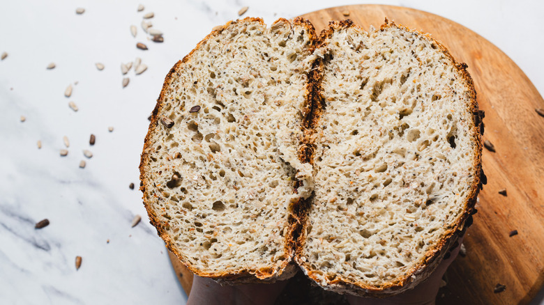 Hands holding bread loaf cut in two