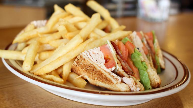 A club sandwich with fries on a plate