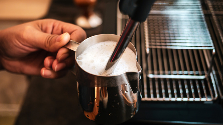 Close-up of a barista steaming milk with an espresso machine