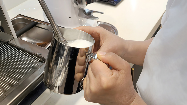 Barista frothing milk with an espresso machine's steam wand