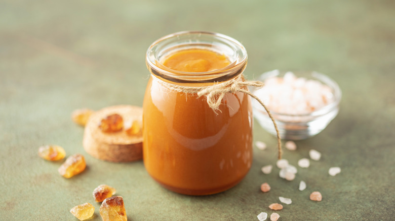 Glass jar of salted caramel salt next to rock sugar chunks and salt crystals