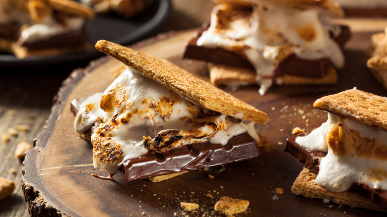 S'mores with graham crackers, chocolate pieces, and toasted marshmallows on wood table