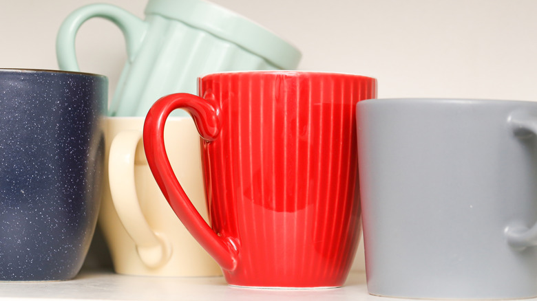 Five assorted mugs on white surface