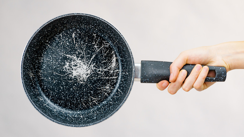 Person holding an old, scratched pan