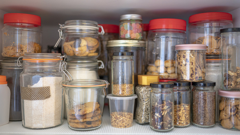 A pantry shelf of jars full of kitchen staples.
