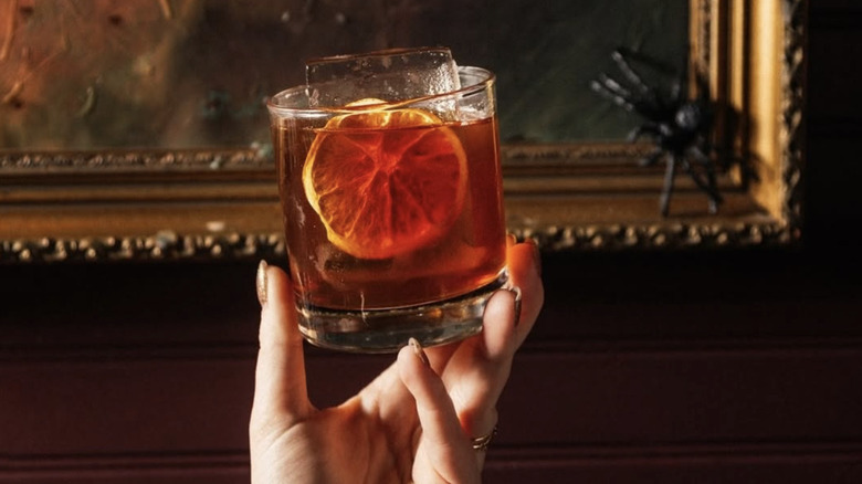 hand holding cocktail in front of gold frame at the Ranstead Room