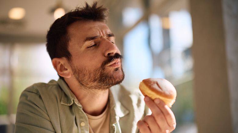 man savors doughnut in sunny shop