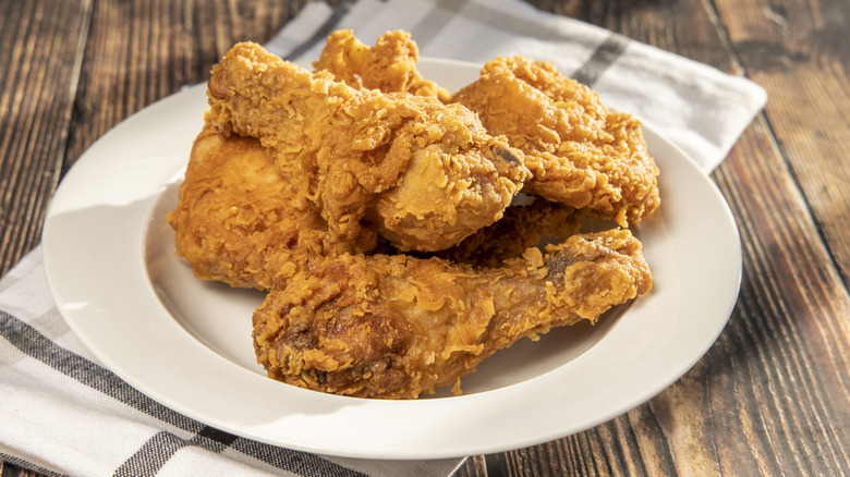 Shallow bowl of fried chicken sitting on a tea towel on a wooden table