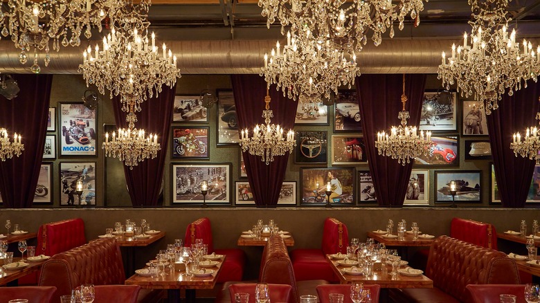 A wall of motorsport photos and chandeliers over empty booths at Town Hearth