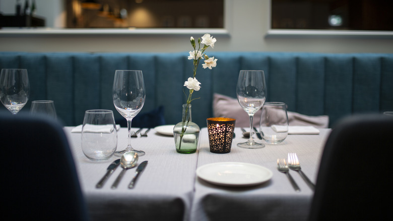 Interior shot of a fancy restaurant, a table with plates, glasses, cutlery, and a flower vase