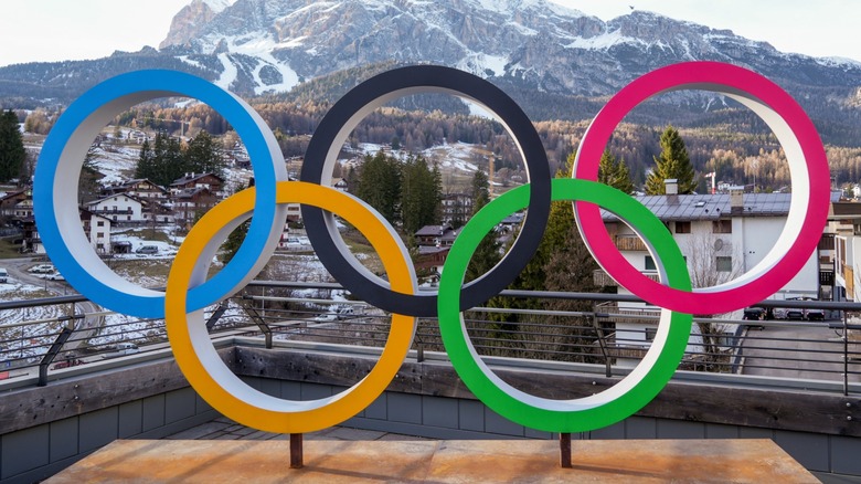 Olympic rings logo sign on display over background of snowy landscape