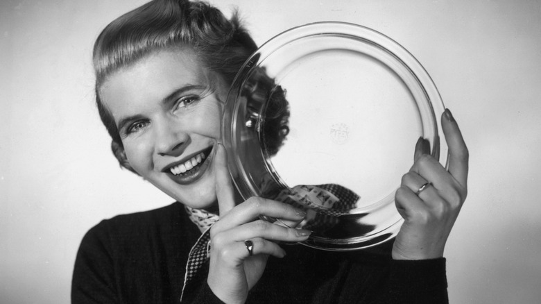 black and white photo of woman holding up glass Pyrex dish