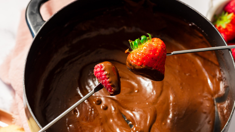 Dipping raspberry and strawberry into chocolate fondue