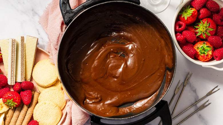 Close up on chocolate fondue for two with berries and cookies