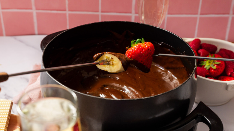 Dipping banana and strawberry into chocolate fondue