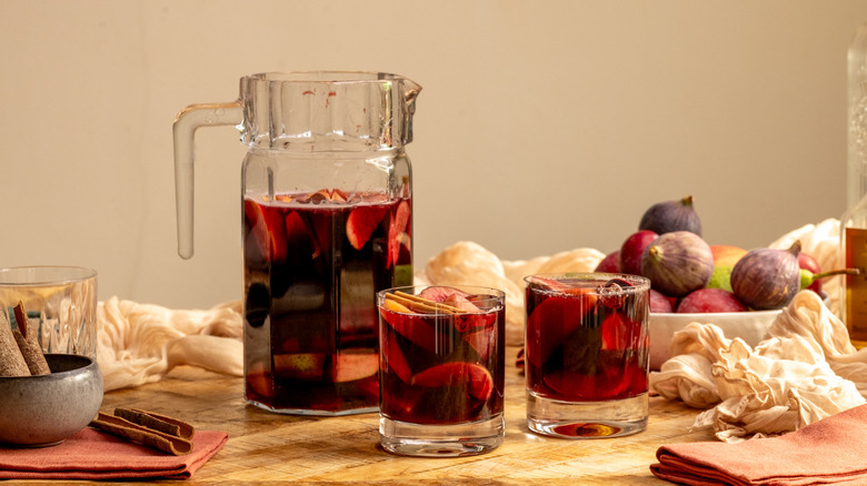 Red sangria in pitcher next to glasses of sangria