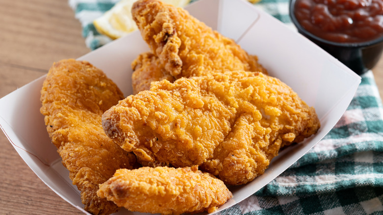 white paper basket with golden fried chicken strips