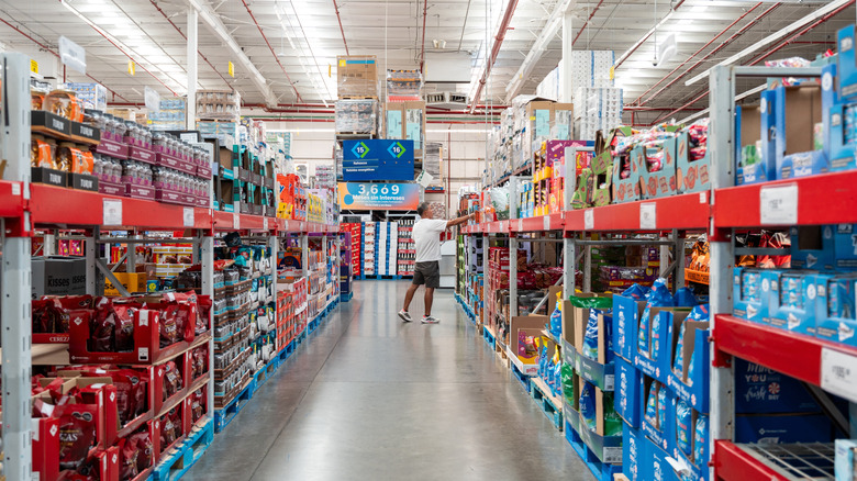 An aisle in Sam's Club with a man pulling an item off a shelf