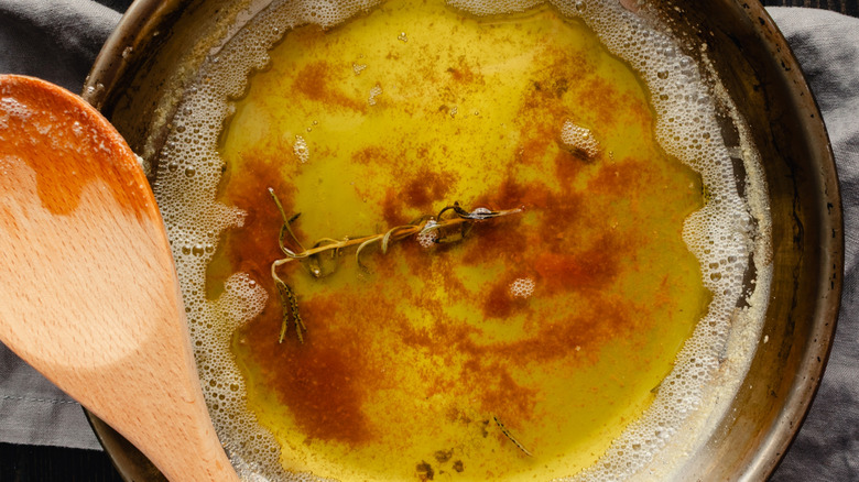 butter being browned in pan with rosemary and wooden spoon