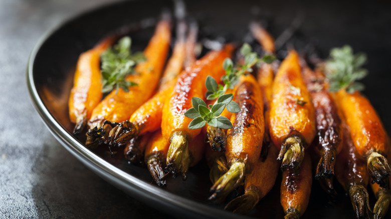 Roasted carrots and herbs in a black bowl