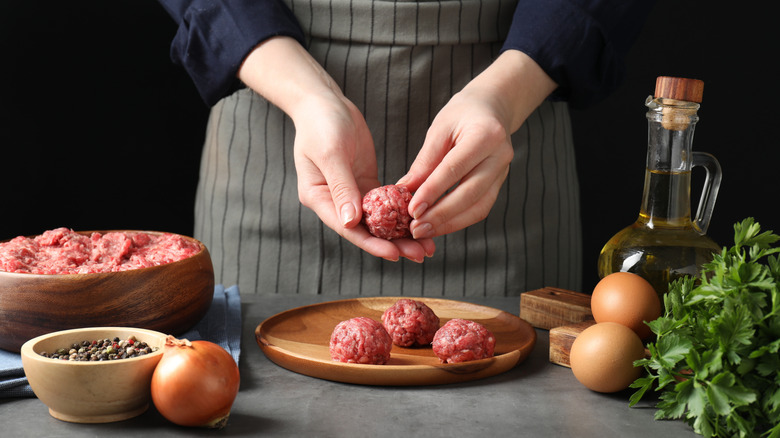 Woman making meatballs with oil, eggs, and herbs