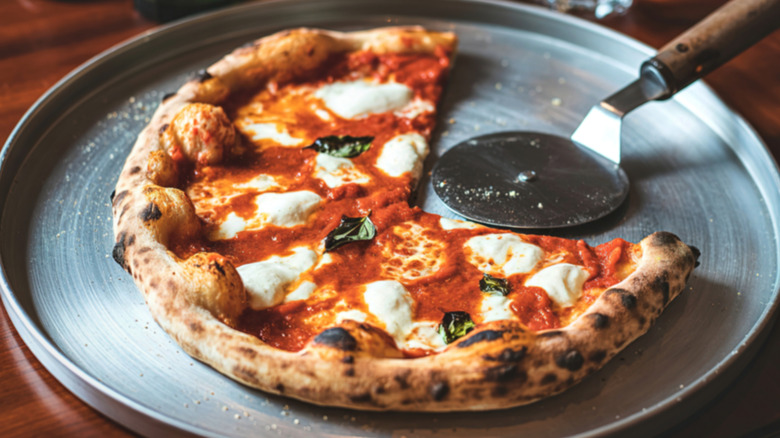 Margherita pizza on a tray with a slice missing