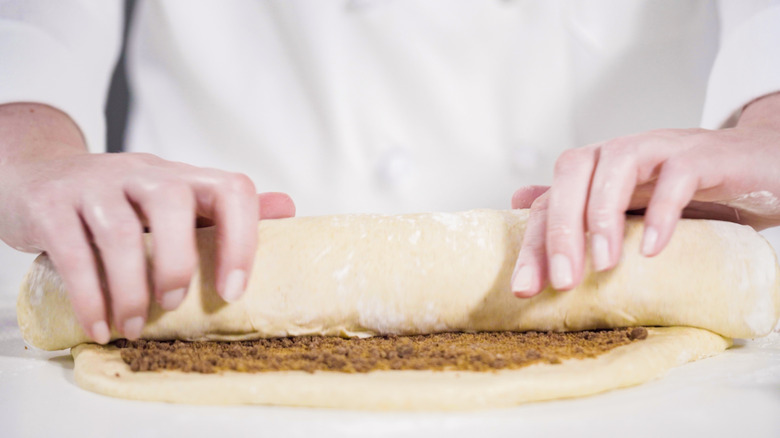 baker rolling dough with cinnamon