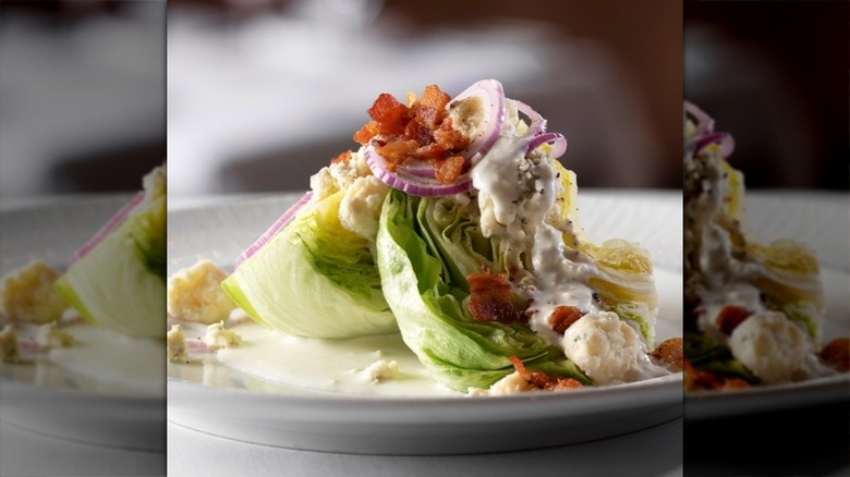 Delmonico Steakhouse's wedge salad with creamy dressing, bacon, red onions, and blue cheese atop wedges of iceburg lettuce.