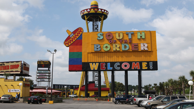 South of the Border signs above several parked cars