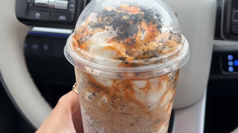 Hand holding a Pumpkin Cookie Crumble Frappuccino in a car